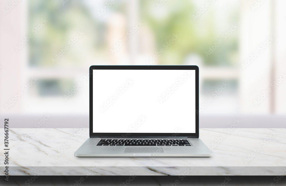 Wall mural laptop with white blank screen on marble table top and blurry image of living room in background.