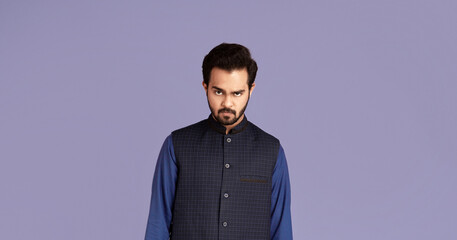 Portrait of strict Indian man in traditional clothes on violet background