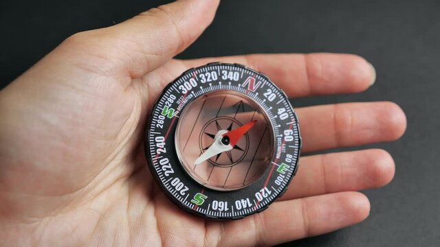 Extreme close-up of a transparent modern compas on the black background. Concept of travel, adventure, expedition