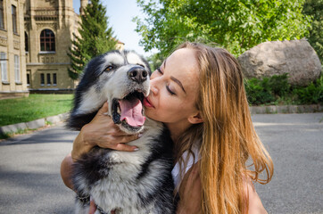 Naklejka na ściany i meble a young beautiful girl gently kisses a husky dog