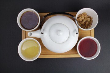 Obraz na płótnie Canvas japanische Teekanne mit kleinen weißen Teetassen und unterschiedlichen Teesorten 