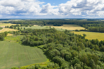 Fototapeta na wymiar Aerial view of green forests surrounded by green farmland fields