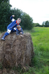 Two boys playing on stack of straw