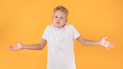 Confused puzzled male kid shrugging at studio