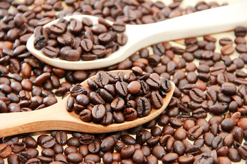 natural black coffee beans in a wooden spoon