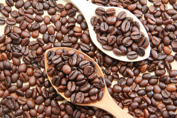natural black coffee beans in a wooden spoon