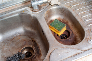 Dirty sink and dish sponge close-up. Unhygienic sink in a kitchen.
