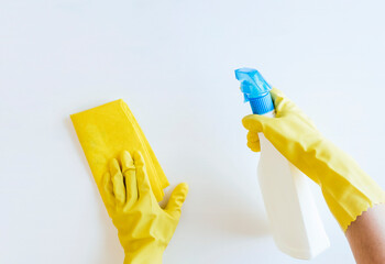 Woman with yellow gloves disinfecting white table