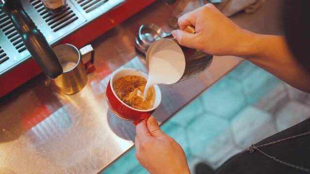 Barista pouring milk in coffee doing latte art.making latte art in cafe