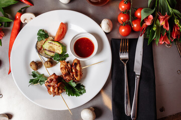Barbecued marinated turkey or chicken meat shish kebab skewers with ketchup sauce and grilled vegetables on rustic wooden table background