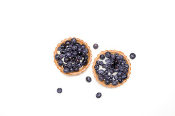 Delicious fresh dessert tartlet of shortbread decorated with fresh blueberries among berries. The concept of baking bakery, sweet food. Close-up photo, isolated, copy space.