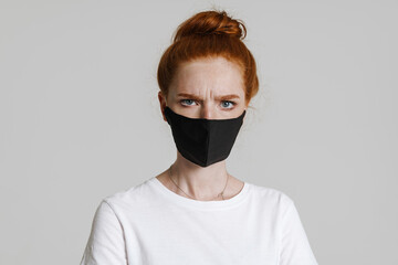 Image of displeased girl in face mask posing and looking at camera