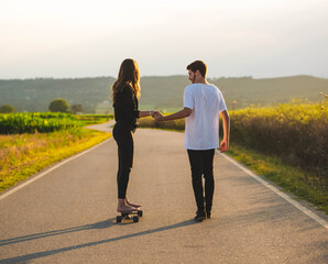 Fototapeta premium A young Caucasian couple learning to skate in the street, A shallow focus shot of a beautiful lovely couple having fun together