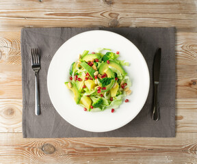 Green Salad with Avocado, Cucumber and Nuts on White Plate
