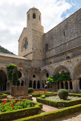 Fototapeta na wymiar The beautiful backyard with ancient stone architecture and the blossoming garden of the medieval christian abbey in the mountain valley of Pyrenees in France