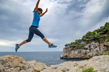 Girl jumping ina cliff close to the sea