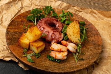 Grilled octopus tentacle on a wooden plate served with shrimps © ange1011