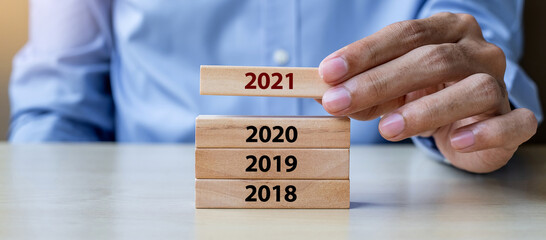 Businessman hand pulling 2021 wooden building blocks on table background. Business planning, Risk...