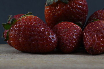 
some strawberries on a wooden board with a black background