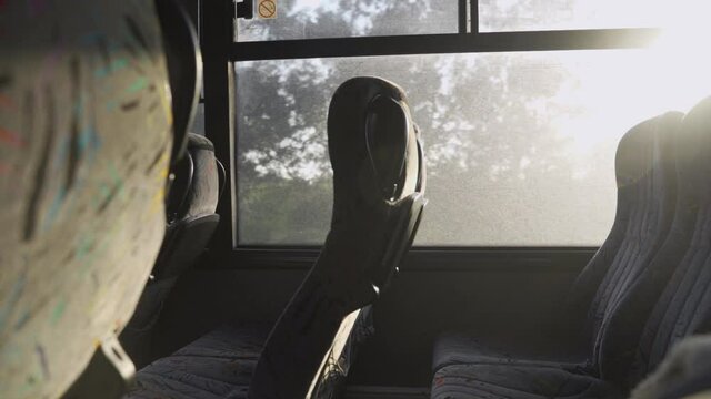 Empty public long distance bus driving on highway road with sun shining bright through windows. Vacant seats by window