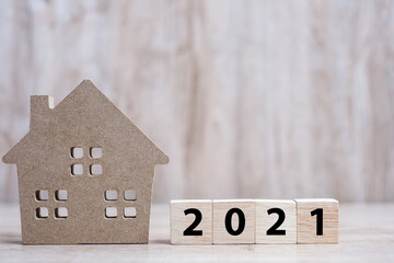 2021 Happy New Year with house model on table wooden background. Banking, real estate, investment,...