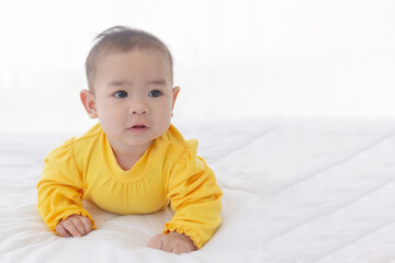 Fototapeta premium An Asian infant lying prone on a clean white bed.