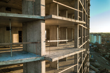 Aerial view of concrete frame of tall apartment building under construction in a city.
