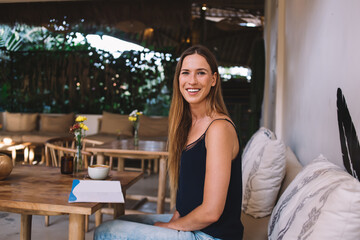 Happy lady sitting at wooden table with cup of coffee and notepad