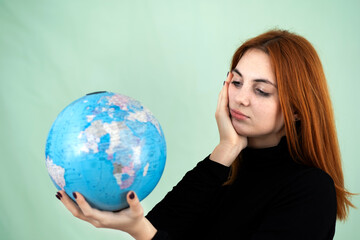 Portrait of a sad worried young woman holding geographic globe of the world in her hands. Travel destination and planet protection concept.