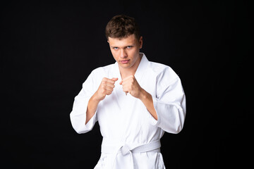 Young man doing karate over isolated black background