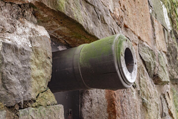  View of a part of the medieval, fortified wall, with a loophole from which you can see the trunk of an old cannon