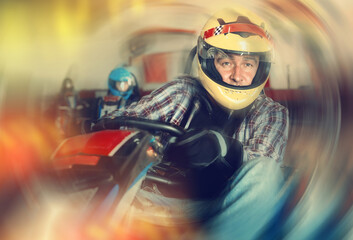 Man driving racing car in a circuit lap in karting club, people on background