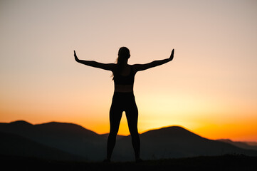 Silhouette woman balanced, practicing meditation, zen energy yoga in mountains. Healthy lifestyle concept. Young girl doing fitness exercise sport outdoors. Morning sunrise. Relax in nature. Back view