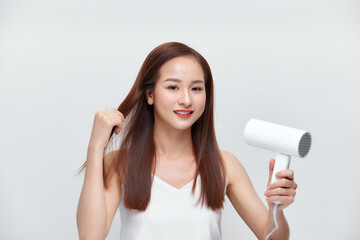 Cute attractive woman holding hairdryer over white background. Looking at camera