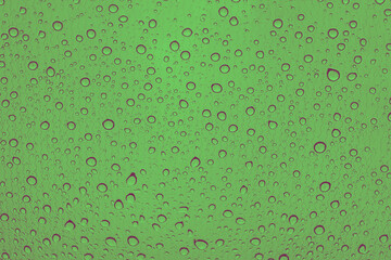 Rain drops on car glass. Green background, toned
