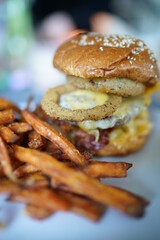Burger with onion rings eggs and sweet potatoe fries