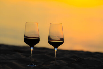 Red wine glasses on the beach during sunset, celebration concept