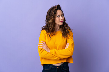 Young caucasian woman isolated on purple background looking to the side