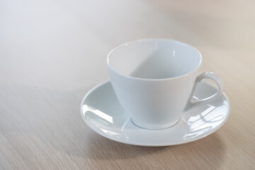 Empty white cup on wooden table.