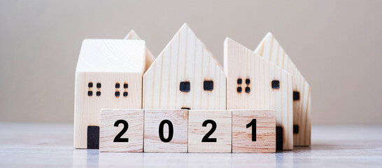 2021 Happy New Year with house model on table wooden background. Banking, real estate, investment,...