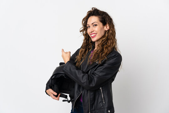Young caucasian woman holding a motorcycle helmet pointing back