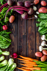 Flat lay of fresh vegetables and greenery on wooden table top-down copy space