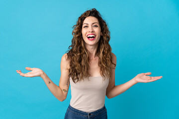Young caucasian woman isolated on blue background with shocked facial expression