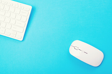 White keyboard and mouse on blue background, top view.