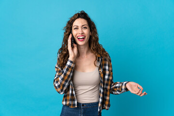 Young caucasian woman isolated on blue background keeping a conversation with the mobile phone with someone