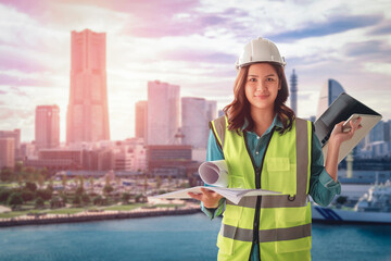 Female Civil engineer with computer and blueprint is standing infront of Japan Yokohama Skyscraper City for city development.