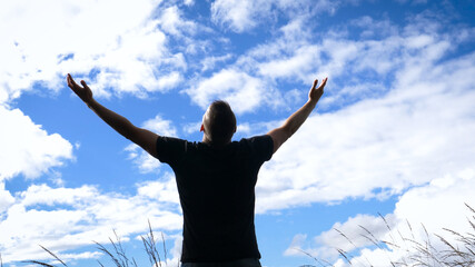 Reach out for the sky - A man opens out his arms facing a vibrant misty sky standing on top of a hill.