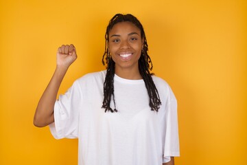 Young dark skinned woman with braids hair wearing casual clothes trendy isolated over yellow background pointing up with fingers number ten in Chinese sign language Shi © Roquillo