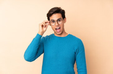 Man over isolated background with glasses and surprised