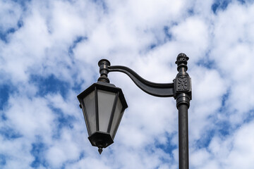Fototapeta na wymiar Metal street lamp in classic style against blue sky.